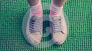 Gray sneakers on female legs on a green background