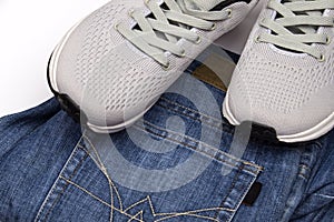 Gray sneakers and jeans. Clothing for walking. Clothing for travel. Sport shoes and blue jeans. Men`s shoes on a white background