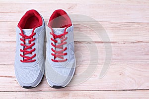 Gray sneakers running with red laces on a wooden background