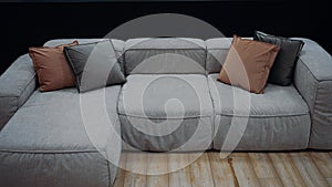 Gray sofa with brown and dark gray cushions, dark background. 4k video