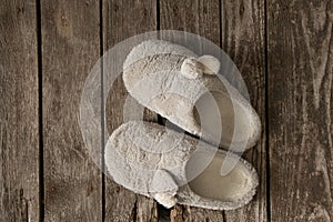 Gray soft house slippers stand on the wooden floor