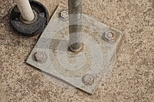 Gray square iron plate with pipe bolted into concrete floor