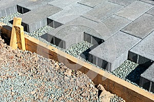 Gray stone pavers installation. Pavers installed in a running bond pattern on a gravel base next to wooden formwork photo