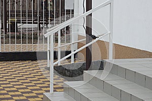 Gray stone steps and a threshold with white metal handrails