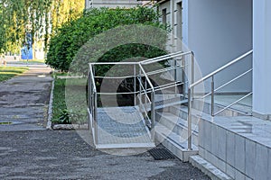 Gray stone steps and a threshold with white metal handrails