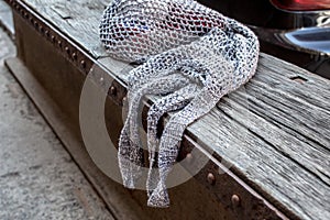 Gray string bag with red knitting clews on old wood texture background