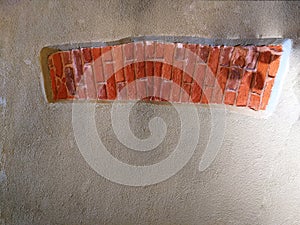 Gray stucco wall with piece of red brick texture. Lintel on an empty wall