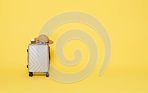 gray suitcase with sunglasses, hat and passport isolated on yellow copy space background. accessories travel concept
