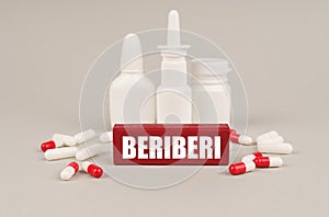 On a gray surface are pills, white jars and a red wooden block with the inscription - beriberi