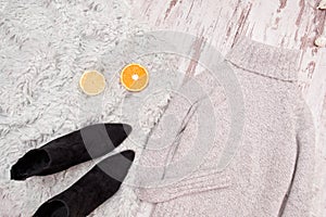 Gray sweater on a wooden background. Halves of orange and black boots. Fashionable concept