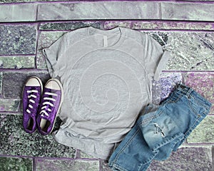 Gray T Shirt mockup flat lay on purple brick background with purple shoes and ripped jeans photo