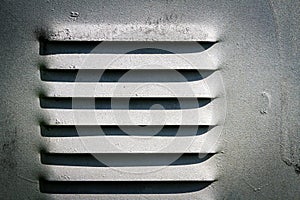 Gray ventilation grille in metal wall