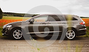 Gray wagon car standing on the background of a field of red poppies