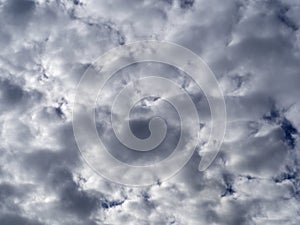 Gray-white cumulus clouds in a dark blue sky. Natural gray background of a rainy overcast landscape