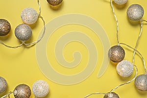 Gray white festive garland on yellow background flat lay top view. Cotton Balls Garland. Round bulbs LED festoon lights electric