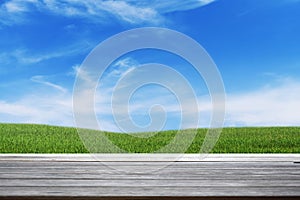 Gray wooden floor texture of terrace with fresh green grass under the blue sky, clouds and sunlight of summer, use for background