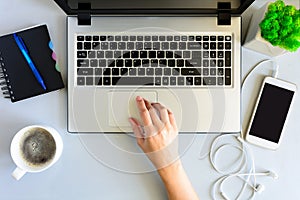 Gray wooden office desk table with laptop computer, smartphone,notebook, pen and cup of coffee.