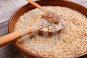 Collecting dry cereals. On a wooden background, buckwheat, rice, oatmeal in a large brown plate.
