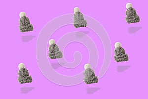 Gray woolen cap whit white pompon pattern on pink  backgound, 3D illustration