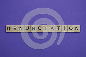 Gray word denunciation in small square wooden letters