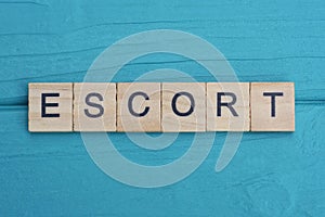 gray word escort from small wooden letters