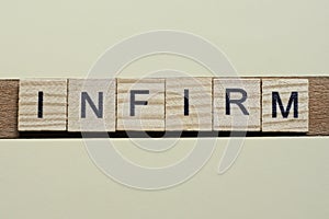 Gray word infirm of gray small wooden letters photo