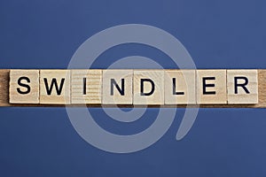 Gray word swindler from small wooden letters photo
