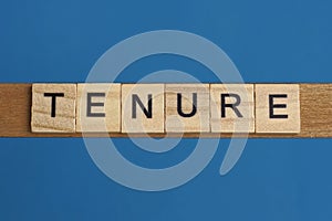 Gray word tenure in small square wooden letters