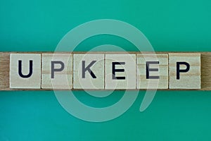Gray word upkeep made of wooden square letters