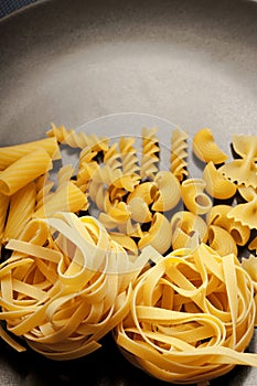 Gray and yellow colors with various kind of pasta and gray background