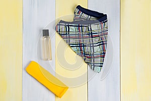 On a gray-yellow surface, a bathing set, men`s swimming trunks and suntan products