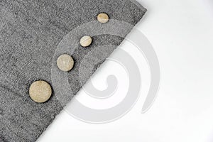 Gray zen pebble hot stones with towel on massage table in beauty salon. Hot stone massage setting.