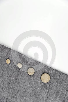 Gray zen pebble hot stones with towel on massage table in beauty salon. Hot stone massage setting.