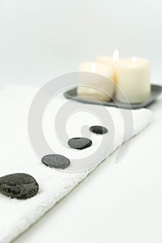 Gray zen pebble hot stones with towel on massage table in beauty salon. Hot stone massage setting.