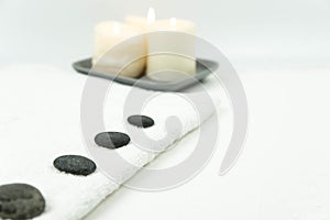 Gray zen pebble hot stones with towel on massage table in beauty salon. Hot stone massage setting.