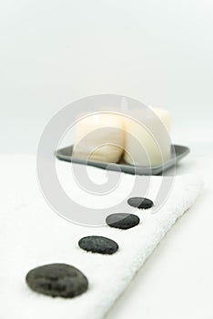 Gray zen pebble hot stones with towel on massage table in beauty salon. Hot stone massage setting.