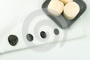 Gray zen pebble hot stones with towel on massage table in beauty salon. Hot stone massage setting.