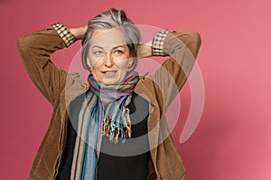 Graying mature woman making hairstyle correcting her hair by hands. creative woman gathered hair on the back of her head