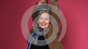 Graying mature woman making hairstyle correcting her hair by hands. creative woman gathered hair on the back of her head