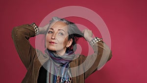 Graying mature woman making hairstyle correcting her hair by hands. creative woman gathered hair on the back of her head