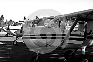 Grayscale of airplanes parked side by side on a paved runway.