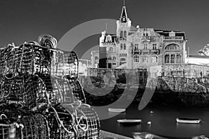Grayscale of beautiful Palacete Seixas in Cascais seen through blurred fishing nets photo