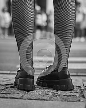 Grayscale closeup of female feet wearing net socks and moccasins with notches soles