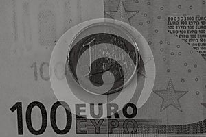 Grayscale closeup shot of details on a hundred Euro banknote and a one euro coin