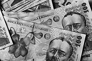 Grayscale closeup shot of a small pile of 100 Romanian leu banknotes