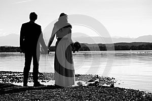 Grayscale of a newly-wed couple standing against the sea