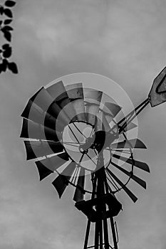 Grayscale of an old water pump windmill in a farm