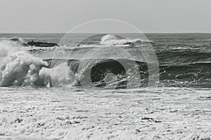 Grayscale shot of big waves crashing on the sea - perfect for background