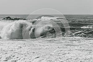 Grayscale shot of big waves crashing on the sea - perfect for background