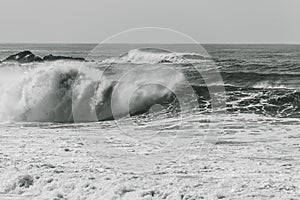 Grayscale shot of big waves crashing on the sea - perfect for background